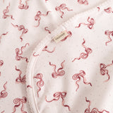 Carpet with bow pattern, reddish-pink on light background, edge and label