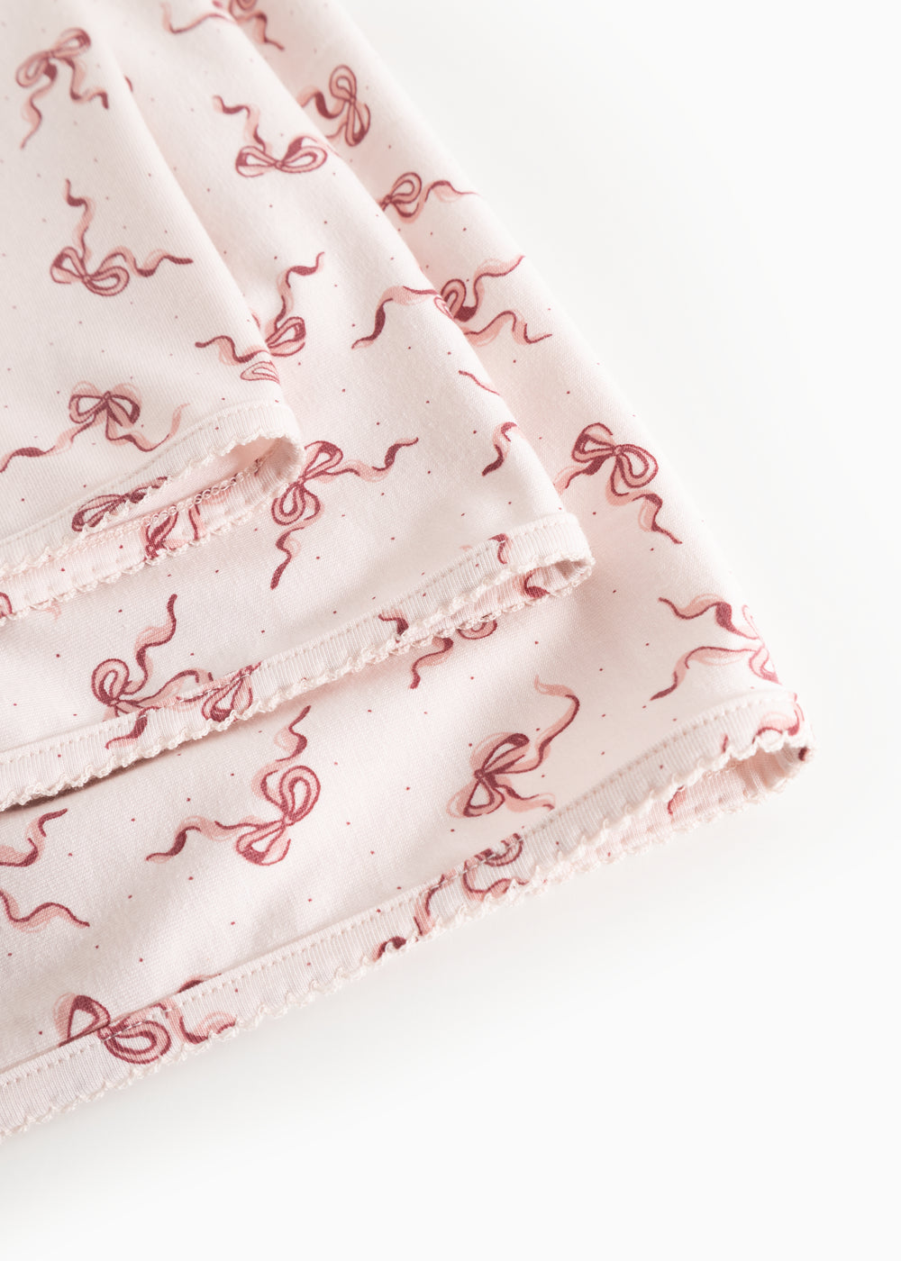 Light fabric blanket with red bow print and visible border.