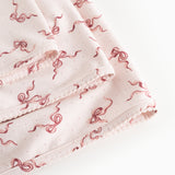 Light fabric blanket with red bow print and visible border.