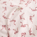 Close-up of carpet: light flat surface with red bow pattern and edge stitching.