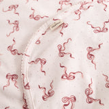Close-up of carpet: light flat surface with red bow pattern and edge stitching.