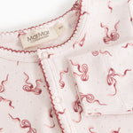 White jumpsuit with pink bow pattern, button and zipper closure at the neck