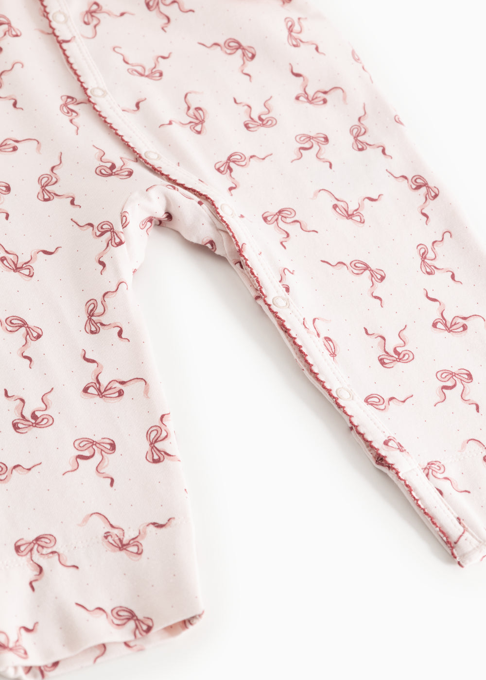 White romper legs with pink bow print and scalloped seam at opening
