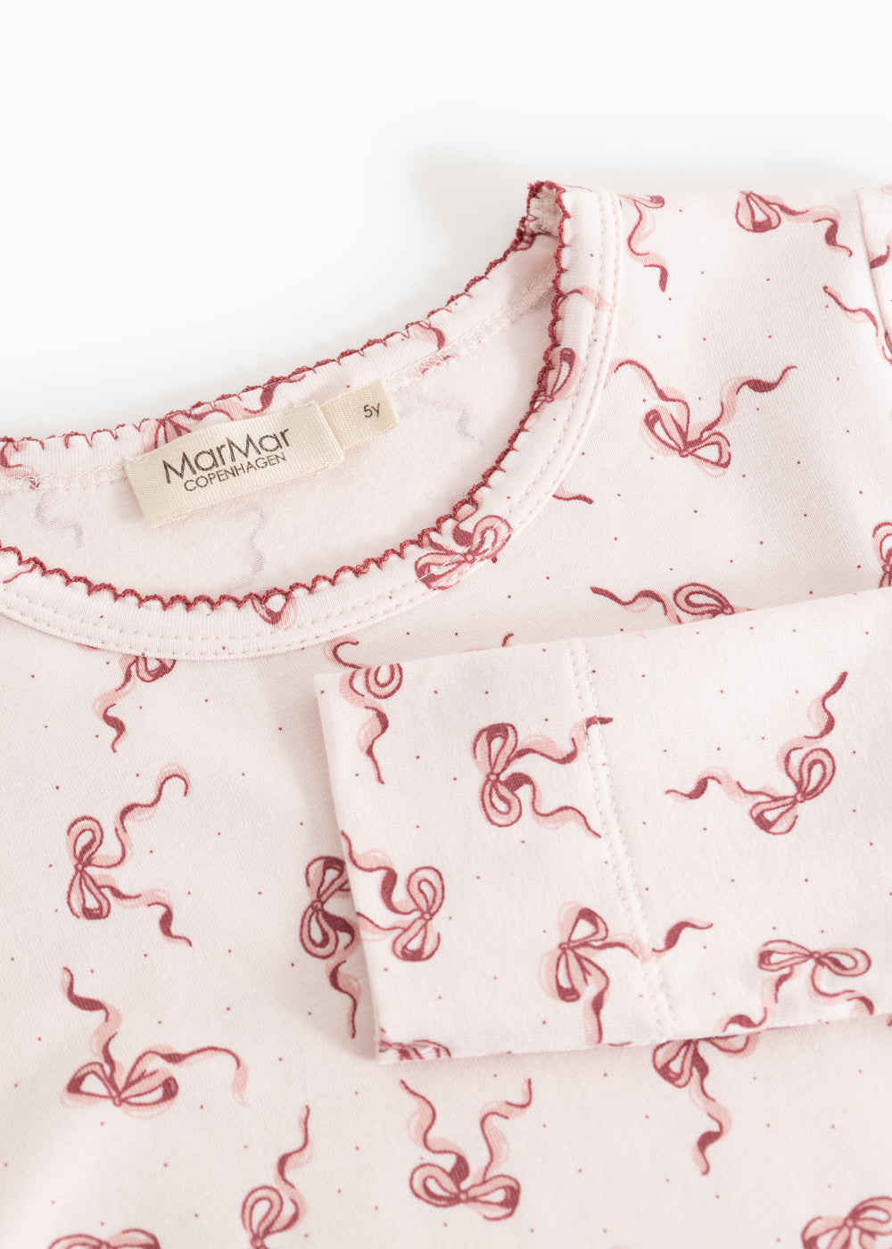 Close-up of a pink neckline with red bow print on nightwear