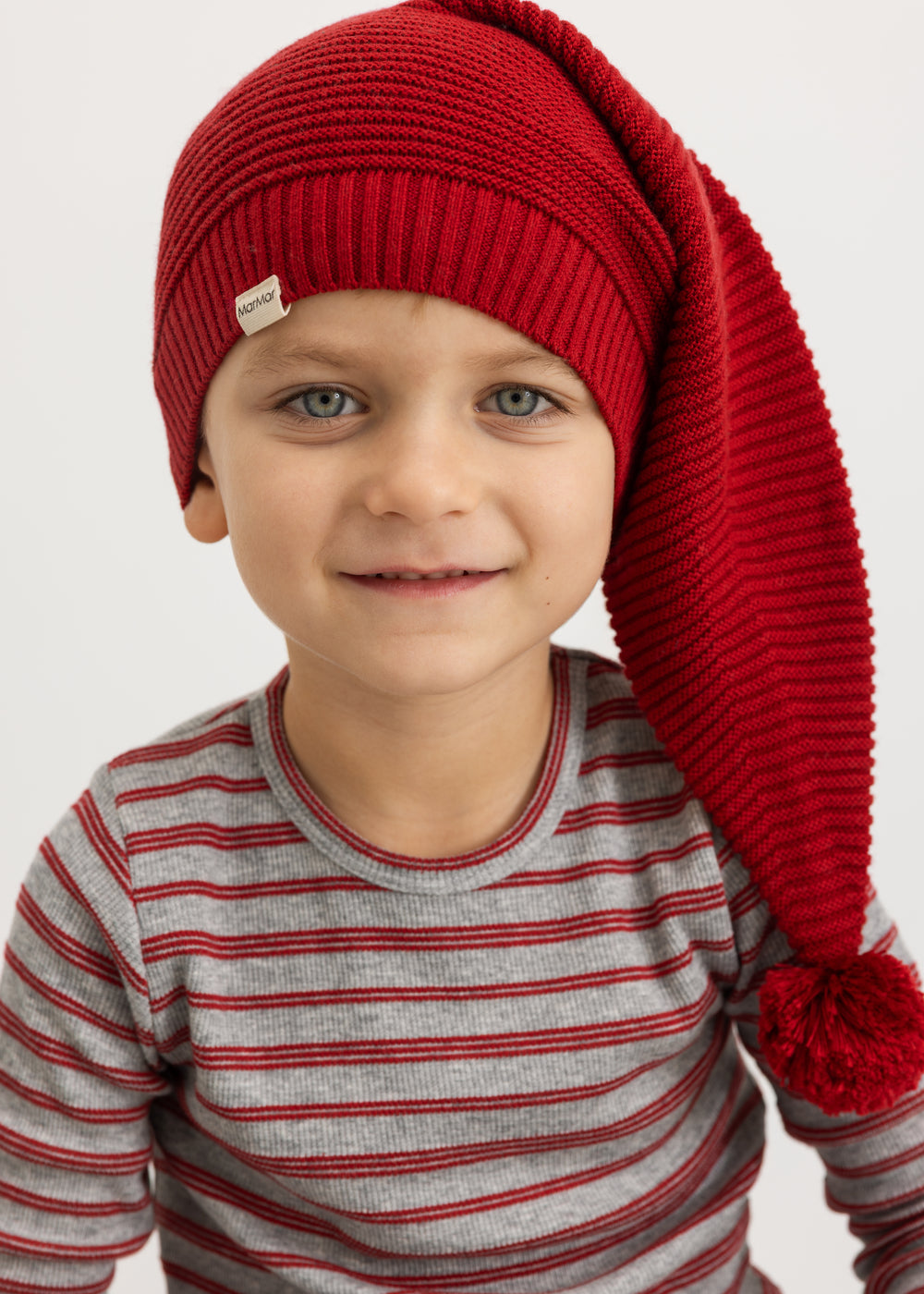 Alfen knitted Santa hat in cherry red with pompom, on a child's head