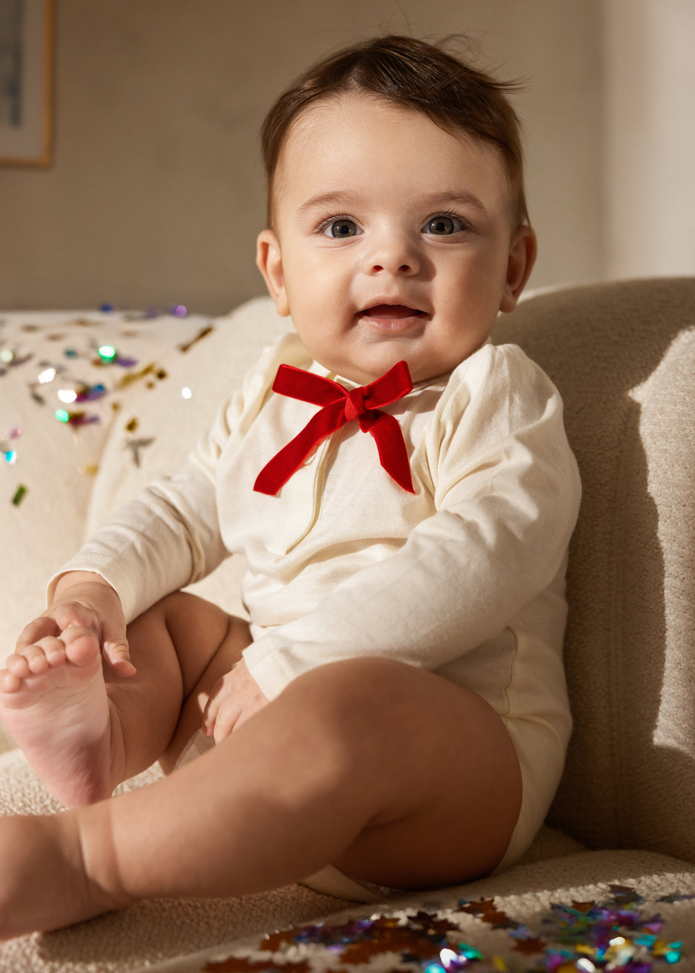 White long-sleeve baby bodysuit with red bow at the chest