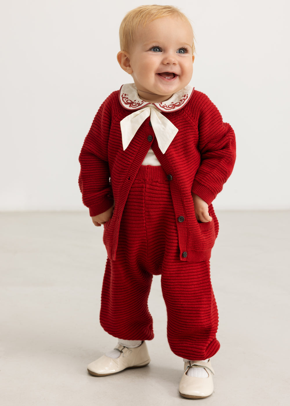 Red knitted overalls with suspenders for baby, shown on child