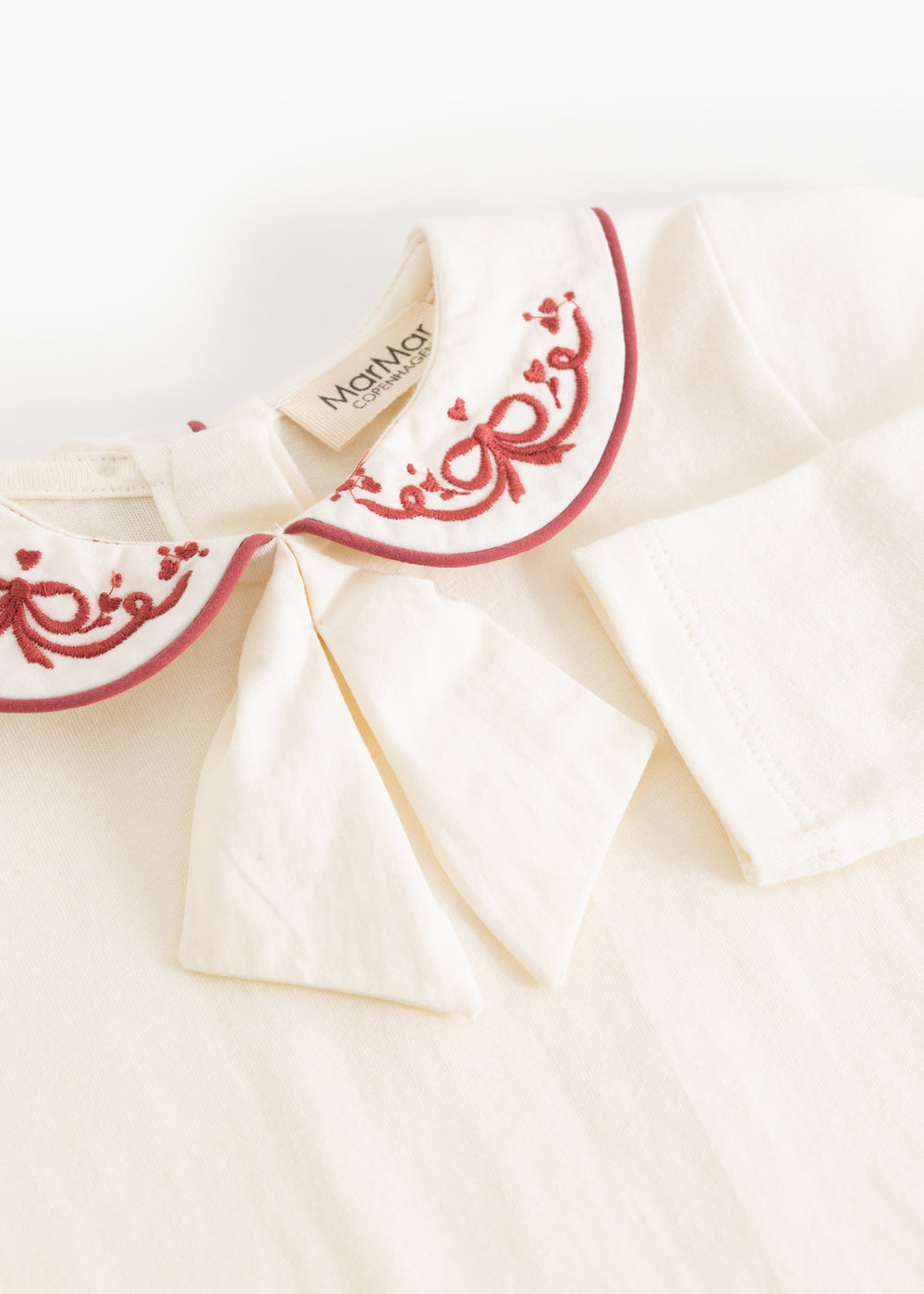 White bodystocking with red collar embroidery and bow-like detail