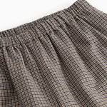 Detail of houndstooth trousers: elastic waistband and pleats at the waist.