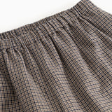 Detail of houndstooth trousers: elastic waistband and pleats at the waist.