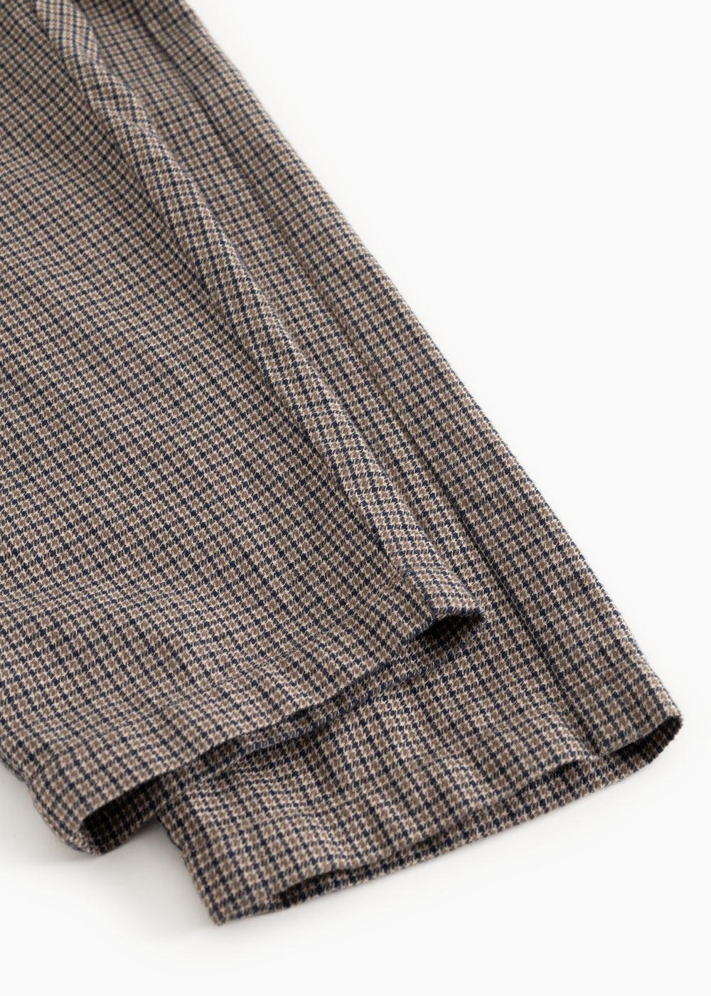 Detail of trouser leg with houndstooth pattern and small cuff at the bottom.