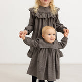 Children's dress with pied de poule pattern, ruffle collar, button closure, and flounce at the bottom of the skirt.