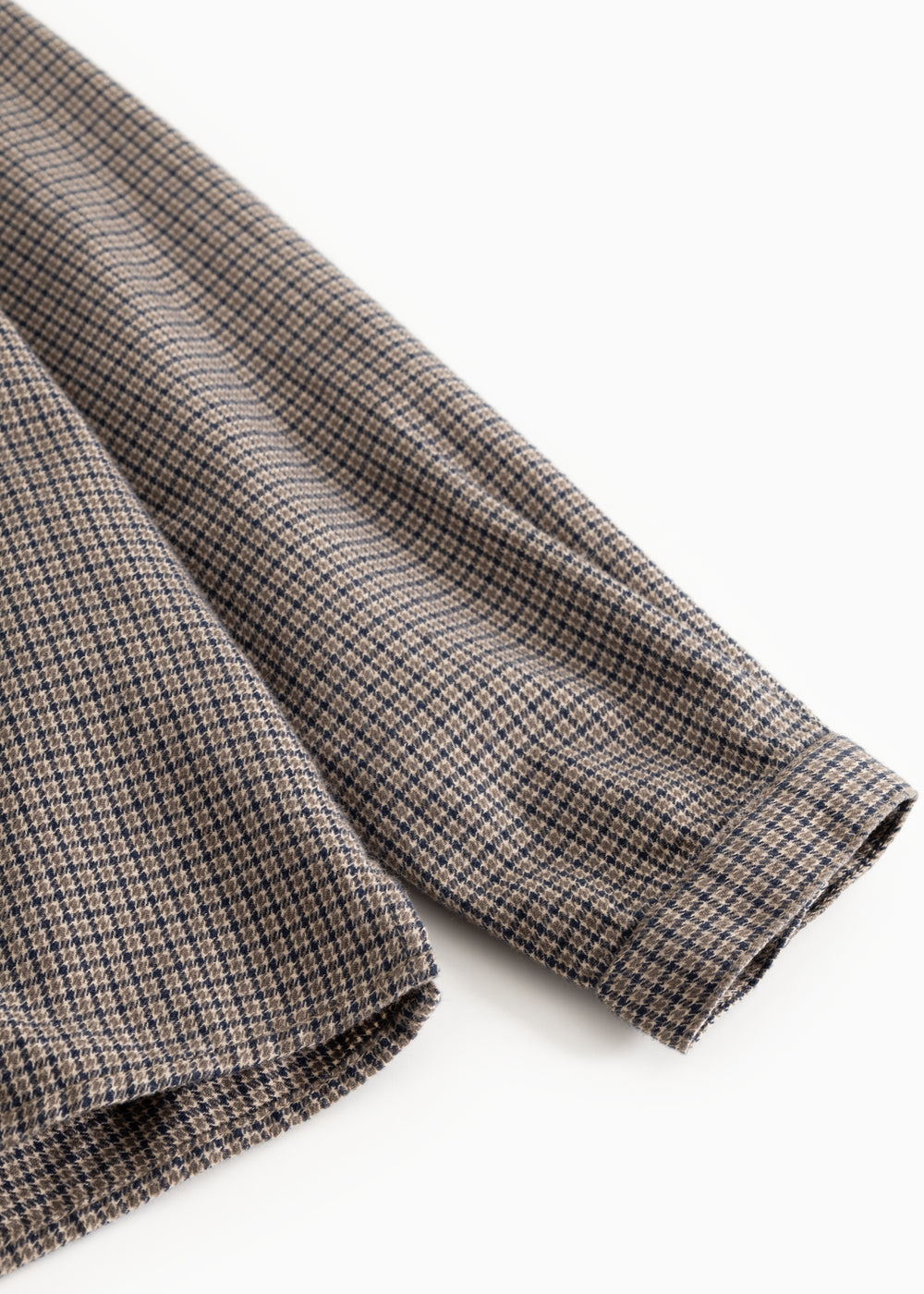 Shirt fabric in houndstooth check, folded sleeves and seam at the edge