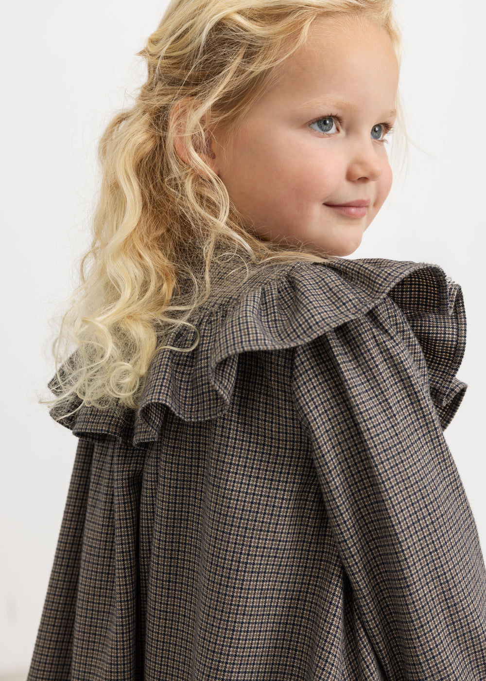 Children's dress with pied de poule pattern, round collar with ruffles, and rolled-up long sleeves.