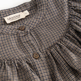 Children's dress with pied de poule pattern, button placket, and ruffle collar with textile label at the neck.