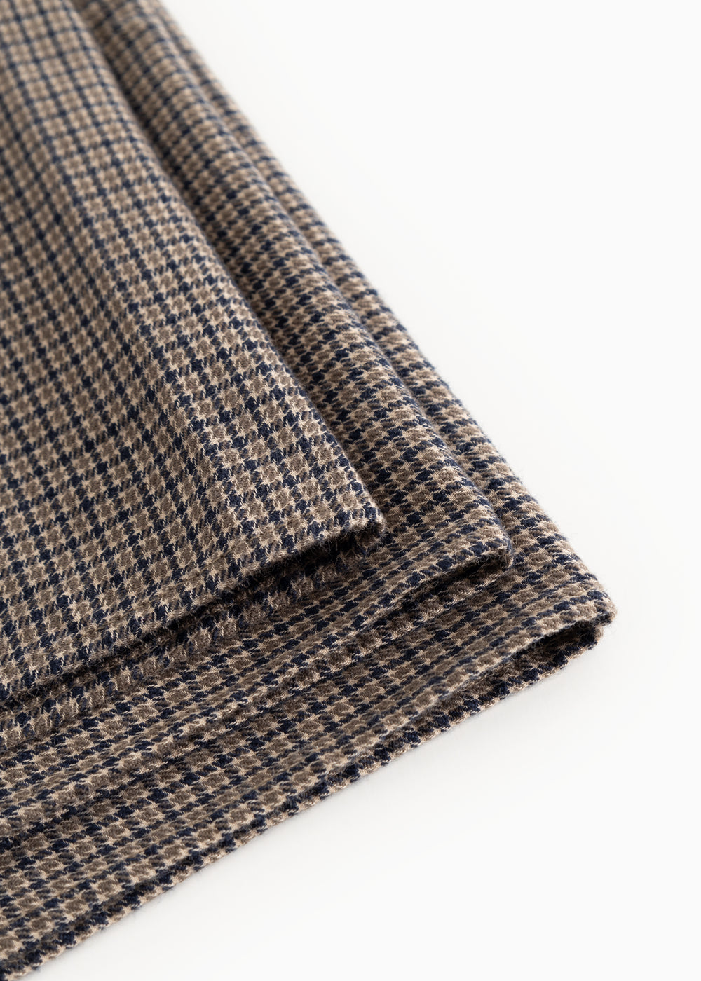 Airo scarf with houndstooth pattern, visible fringed edge and fold in brown and blue