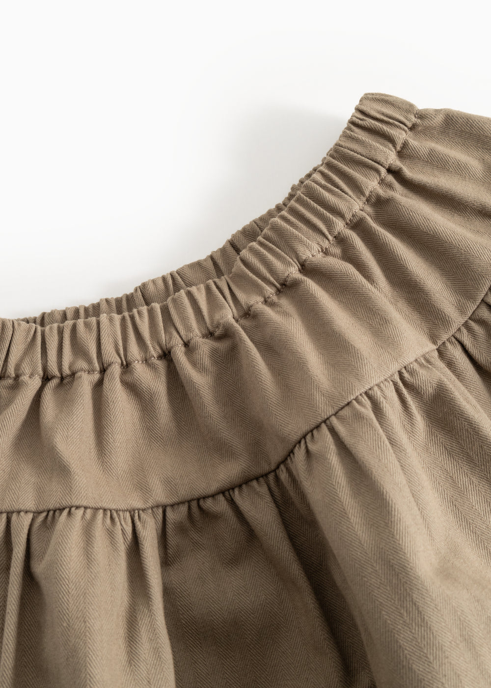Detail: elastic waistband and gathered pleats on brown skirt