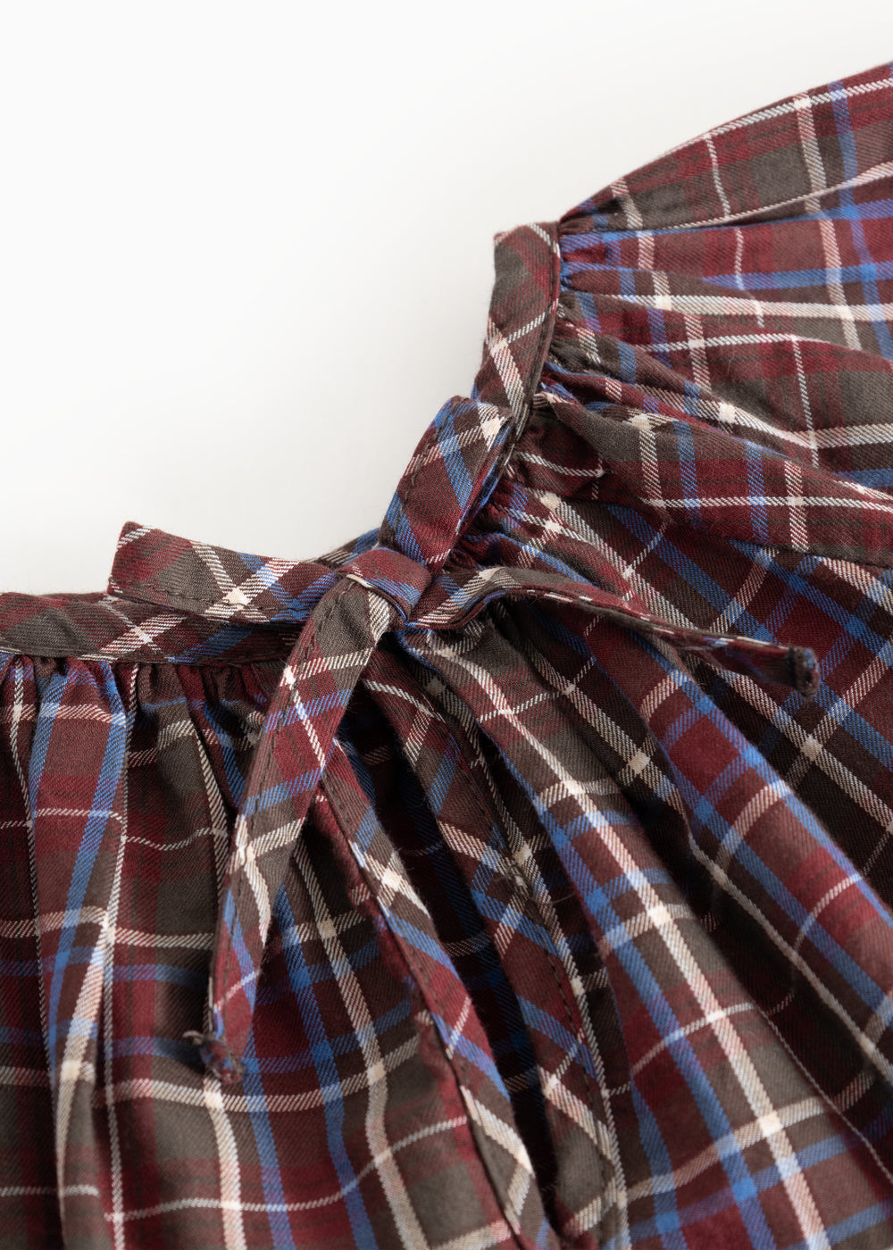 Children's blouse with check pattern and large bow detail at the neckline