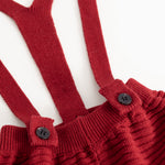 Detail: red knitted suspenders with two buttons on the suspender straps