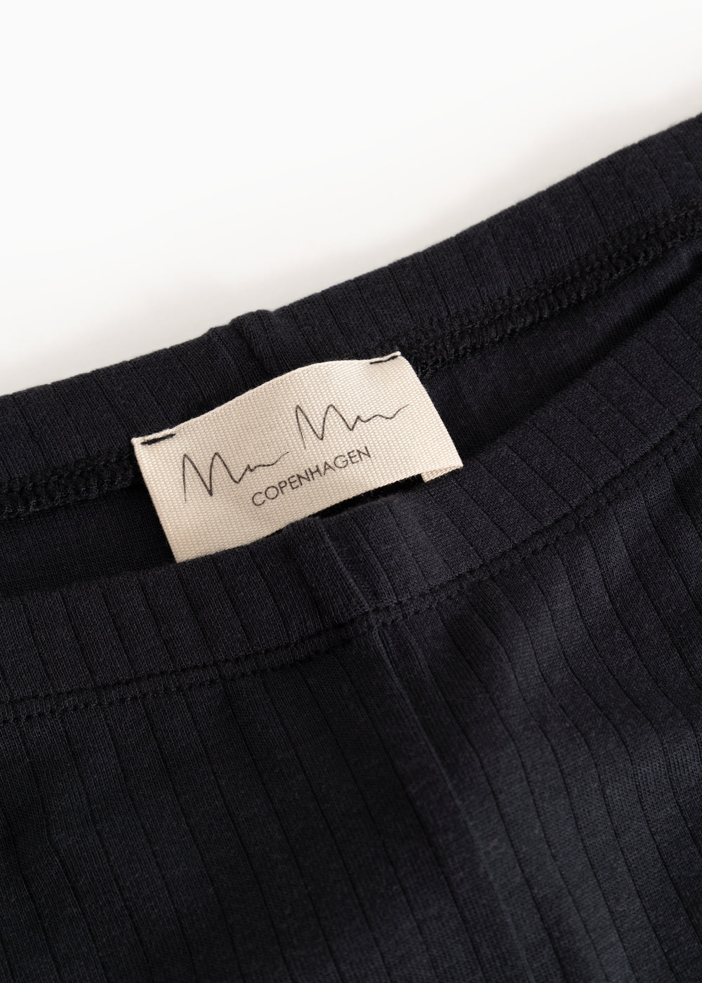 Pants with black ribbed fabric and "m Copenhagen" label at the waist.