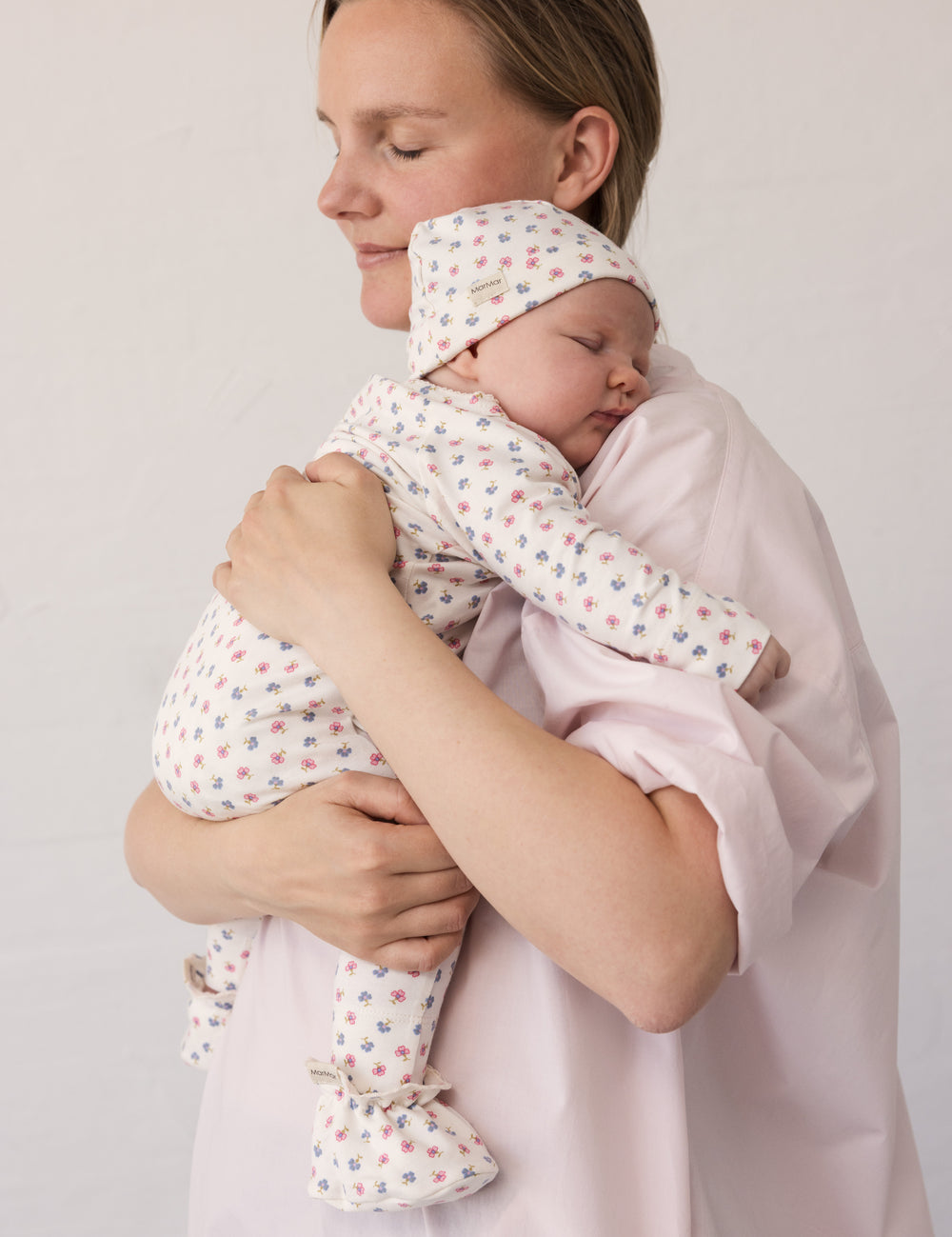 Woman wearing a bright red dress while holding a baby in her arms.