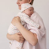 Woman wearing a bright red dress while holding a baby in her arms.