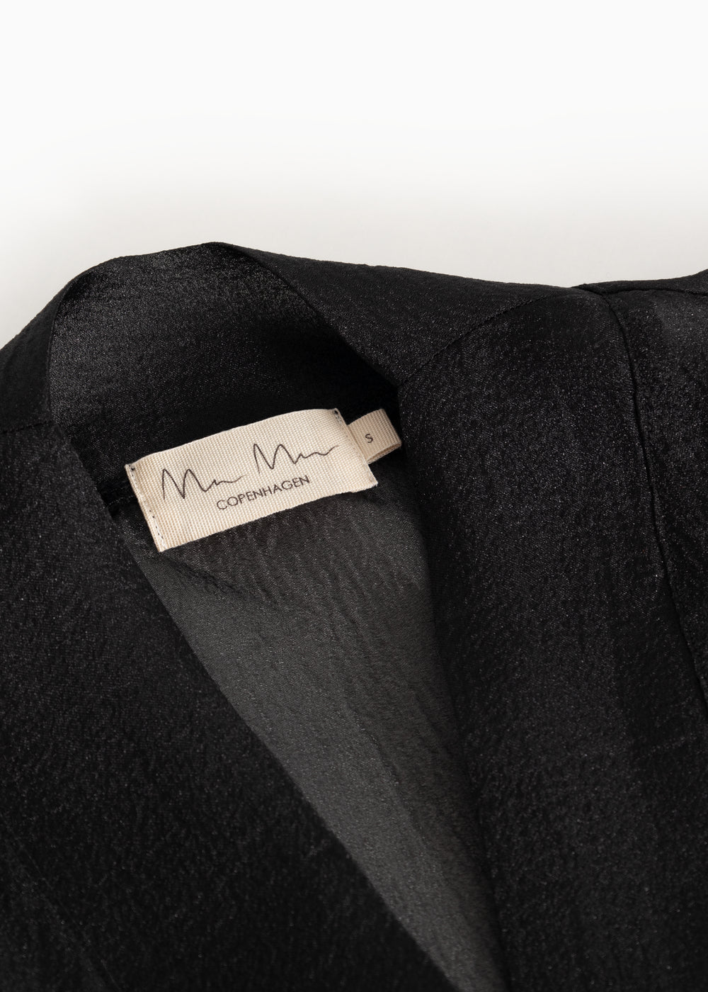 Short dress with round neckline and label at the back of the neck, visible fabric texture