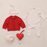 Baby sets with a red cardigan, a sparkly dress with hearts, a hat, and a heart pendant.