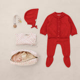 Baby sets with a red cardigan and pants, body with hearts, hat, sash, and toiletries bag.