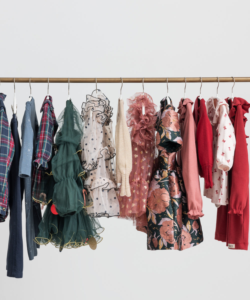 Festtøj og julekjoler til børn hængende på tøjstativ i forskellige farver