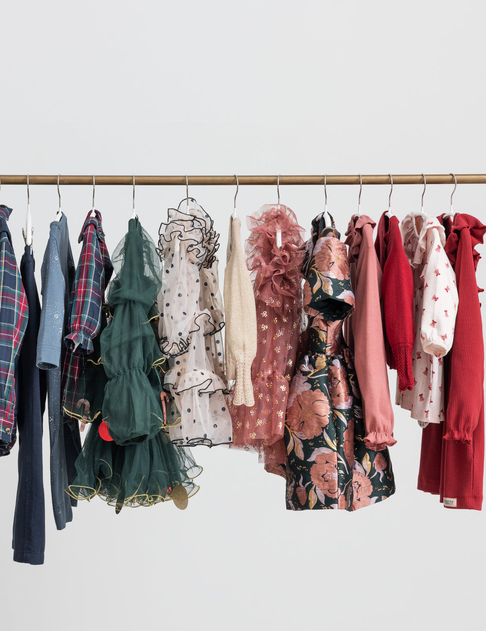Festtøj og julekjoler til børn hængende på tøjstativ i forskellige farver