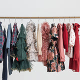 Festtøj og julekjoler til børn hængende på tøjstativ i forskellige farver