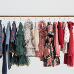 Festtøj og julekjoler til børn i forskellige farver hængende på tøjstativ 