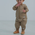 Baby iført beige termotøj - jakke med lynlås, termobukser  og støvler