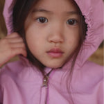 Barn i lyserød overgangsjakke med hætte tæt på ansigtet