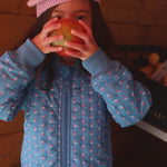 Barn i blå termo jakke med blomstret print og lyserød strikket hue 