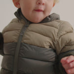 Barn iført vatteret jakke i beige og grønne nuancer