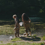 To børn leger udendørs i stribet regntøj ved vand