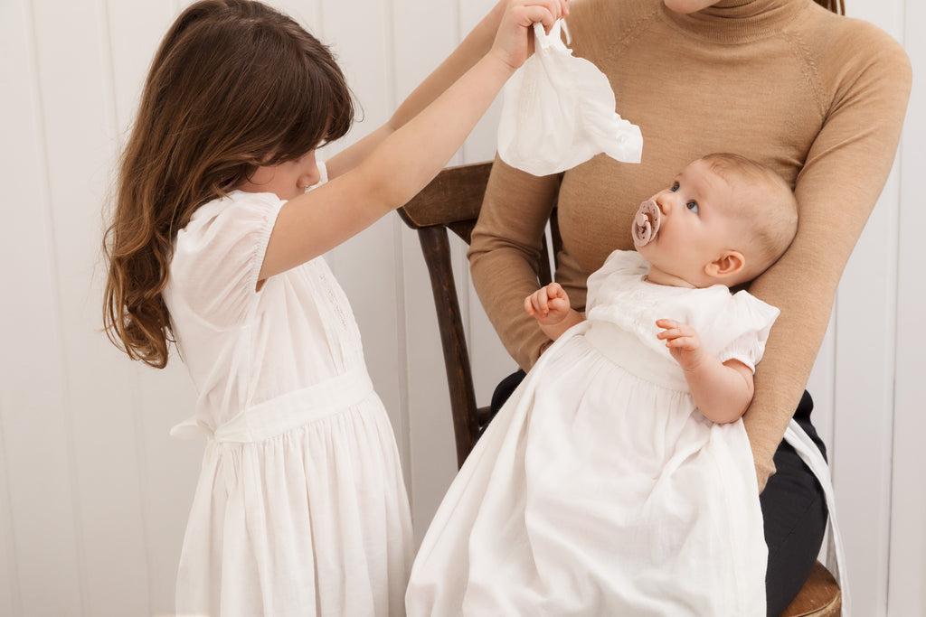 Baby i dåbskjole som får kyse på